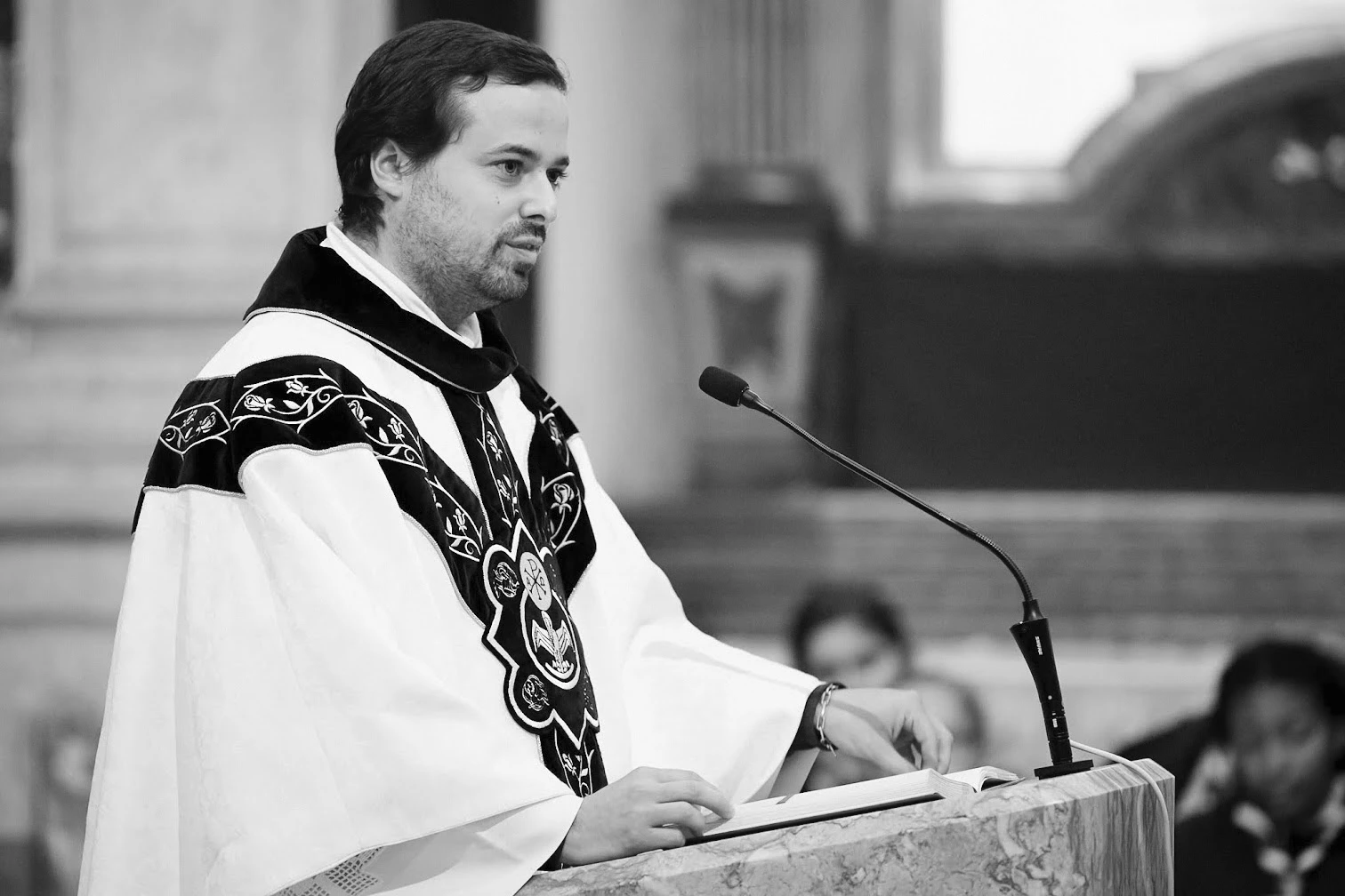 Padre a falar ao microfone durante uma cerimonia
